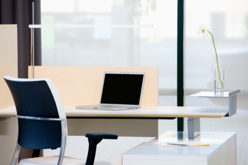 Empty desk with laptop in modern office